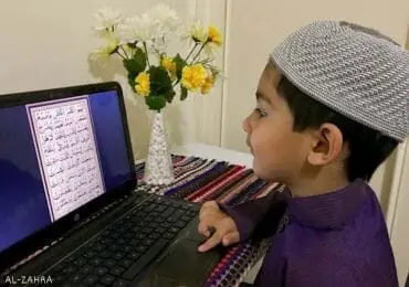 Muslim boy learning Quran online through a laptop, representing online Quran classes for kids at Al Zahra Quran Academy